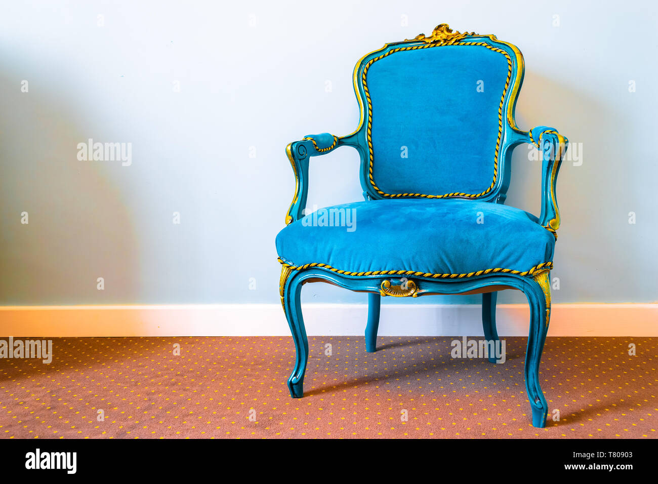 Semplice stile retrò sedia con tessuto blu e giallo ornamenti lussuosi, impostare su un tappeto marrone con motivo maculato. Copia spazio sulla sinistra e morbida, n Foto Stock