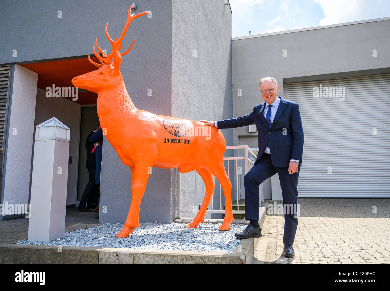 Wolfenbüttel, Germania. Il 10 maggio 2019. Stephan Weil (SPD), il Ministro Presidente della Bassa Sassonia, arriva all'apertura del recentemente allargato impianto di imbottigliamento del produttore di bevande e Jägermeister sorge accanto a un arancione stag scultura con il logo Jägermeister. Con questa espansione, Jägermeister ha, secondo le proprie informazioni, realizzato uno dei più grandi spiriti di impianti di imbottigliamento in Europa. Foto: Christophe Gateau/dpa Credito: dpa picture alliance/Alamy Live News Foto Stock