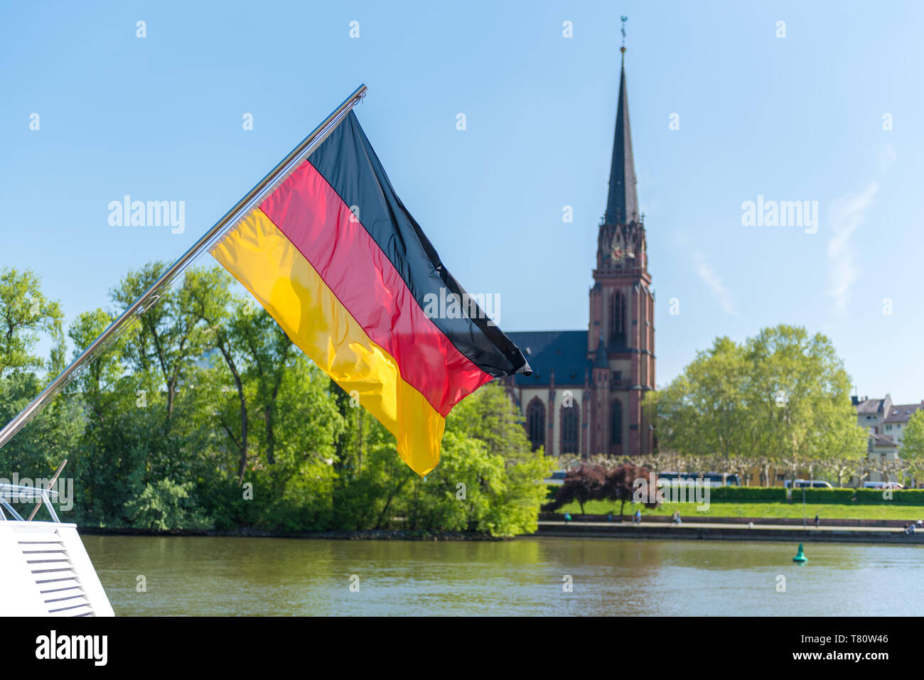 Bandiera tedesca su dtern di una barca sul fiume Main a Francoforte in Germania con la chiesa in background Foto Stock