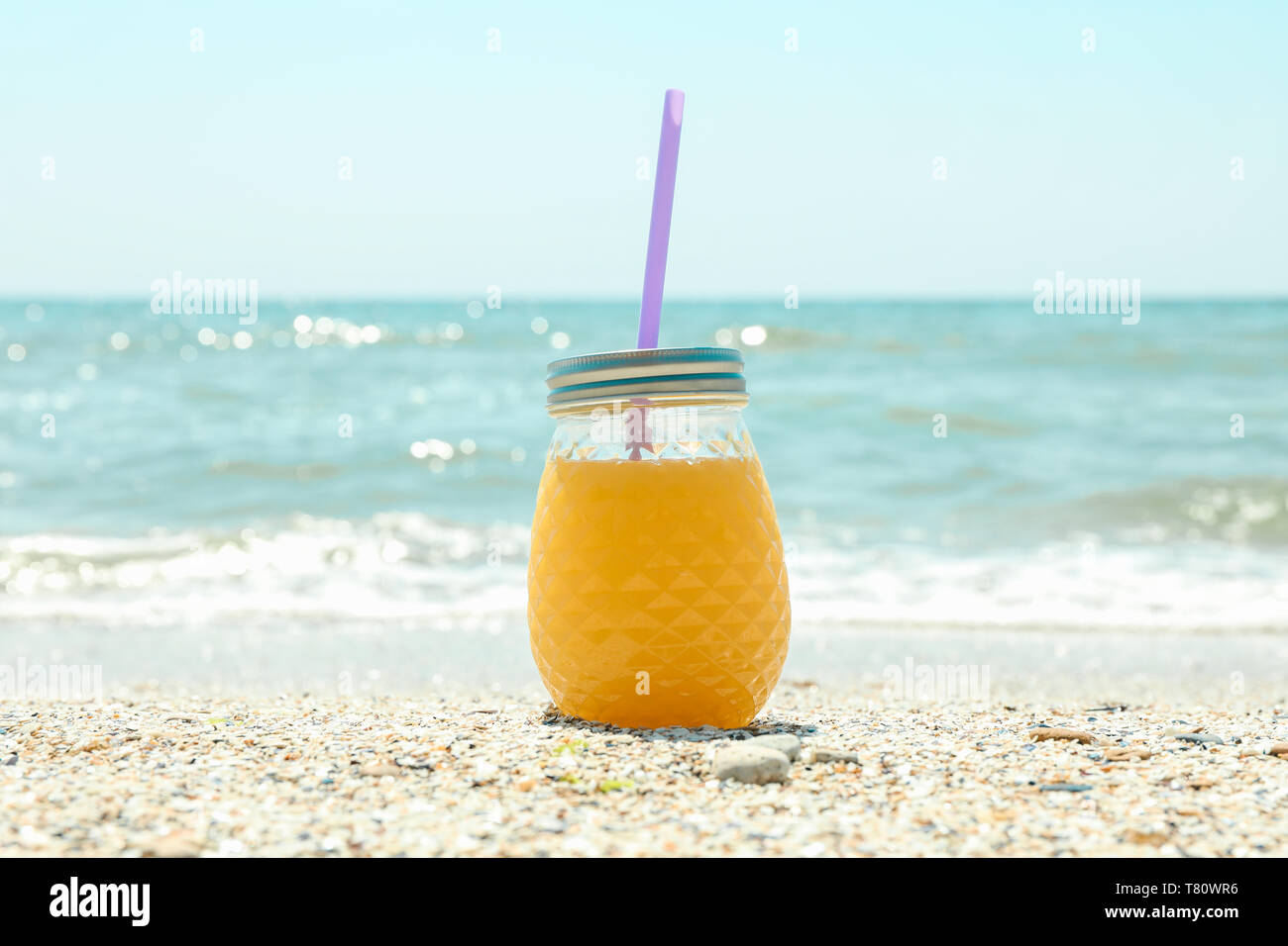 Il vasetto di vetro di succo d'arancia fresco sul mare, lo spazio per il testo. La vacanza estiva lo sfondo Foto Stock