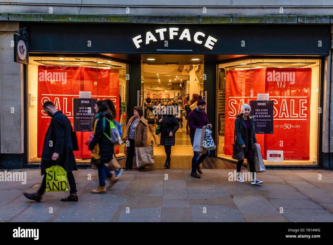Gli amanti dello shopping al di fuori di un Fatface faccia grassa negozio di abbigliamento con manifesti per la pubblicità di una vendita in Windows. Oxford, Regno Unito. Dicembre 2018. Foto Stock