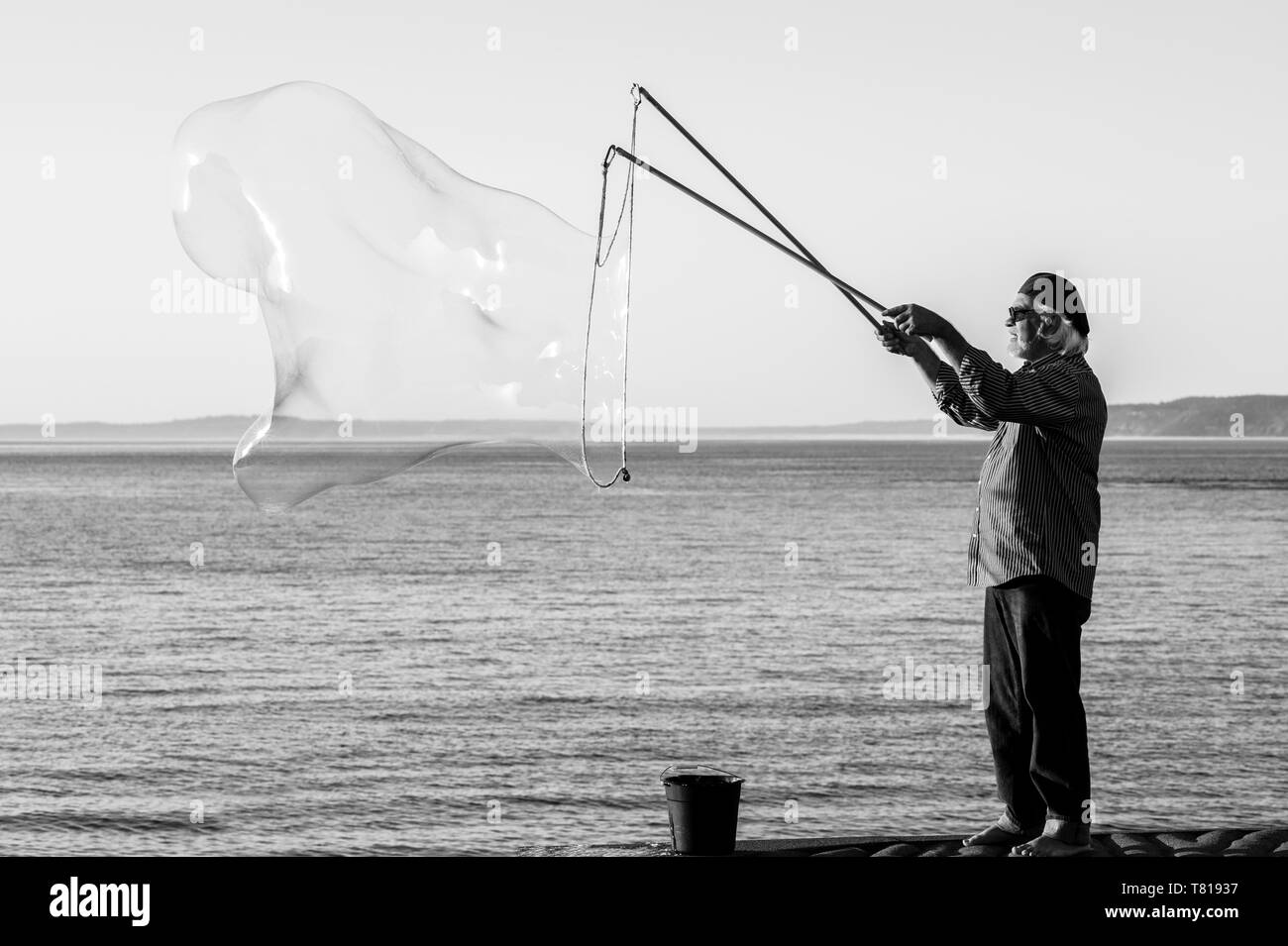 Tramonto lungo Puget Sound con uomo che fa bolle di grandi dimensioni Foto Stock