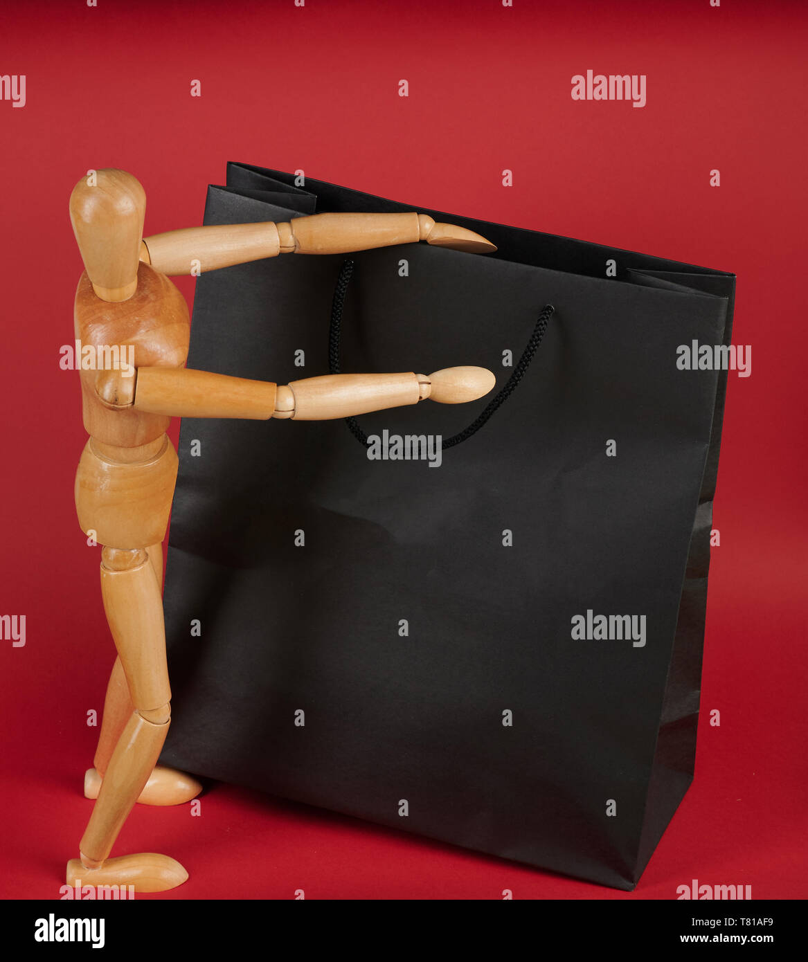 Uomo con grande shopping bag. Il burattino di legno nero di apertura busta di carta Foto Stock