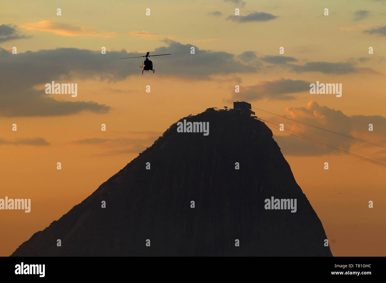 Un elicottero che passa vicino al famoso punto di riferimento Sugarloaf presso sunrise, Rio de Janeiro, Brasile Foto Stock