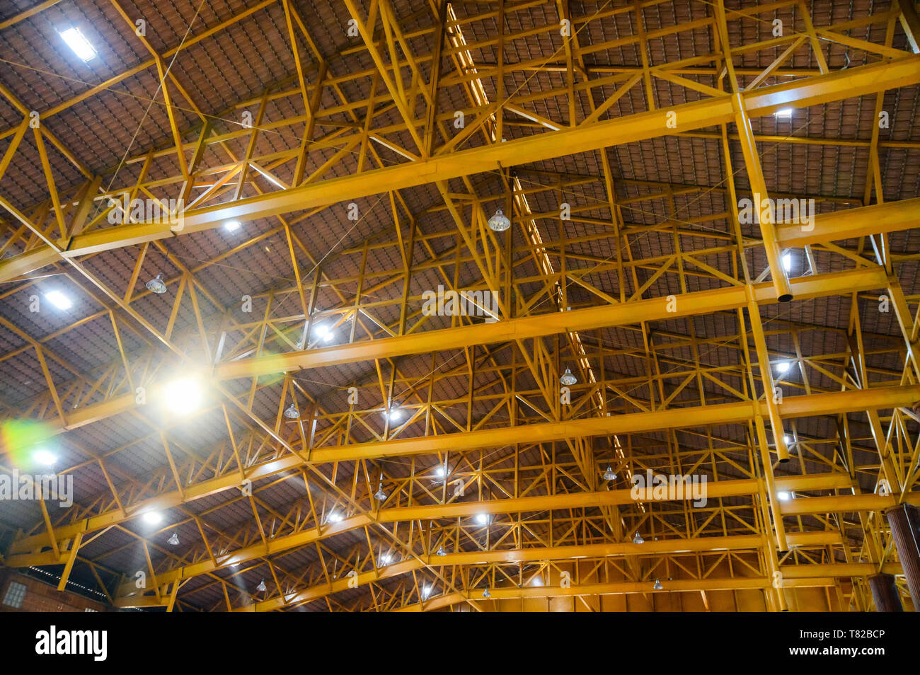 Metallo giallo struttura sul tetto con illuminazione a lampada in magazzino Foto Stock