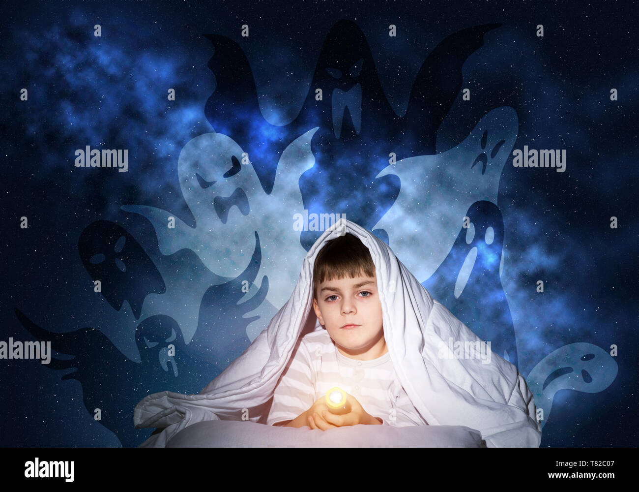 Spaventata ragazzo con la torcia elettrica sotto coperta Foto Stock