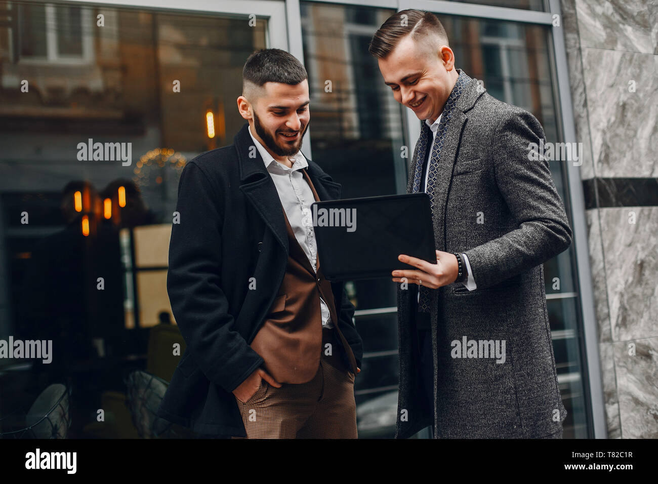 Due uomini belli funzionante. Gli amici di parlare. Uomo in un vestito e un cappotto Foto Stock