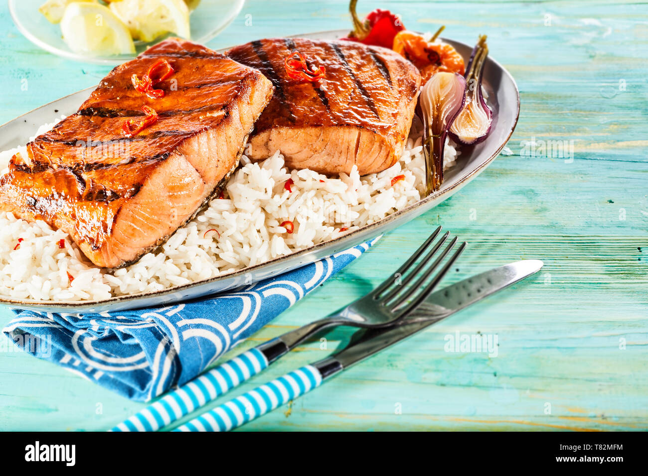 Brace o spessi alla griglia salmone fresco bistecche condito con pepe di caienna Hot Chili Peppers e servita con verdure alla griglia su un letto di riso Foto Stock