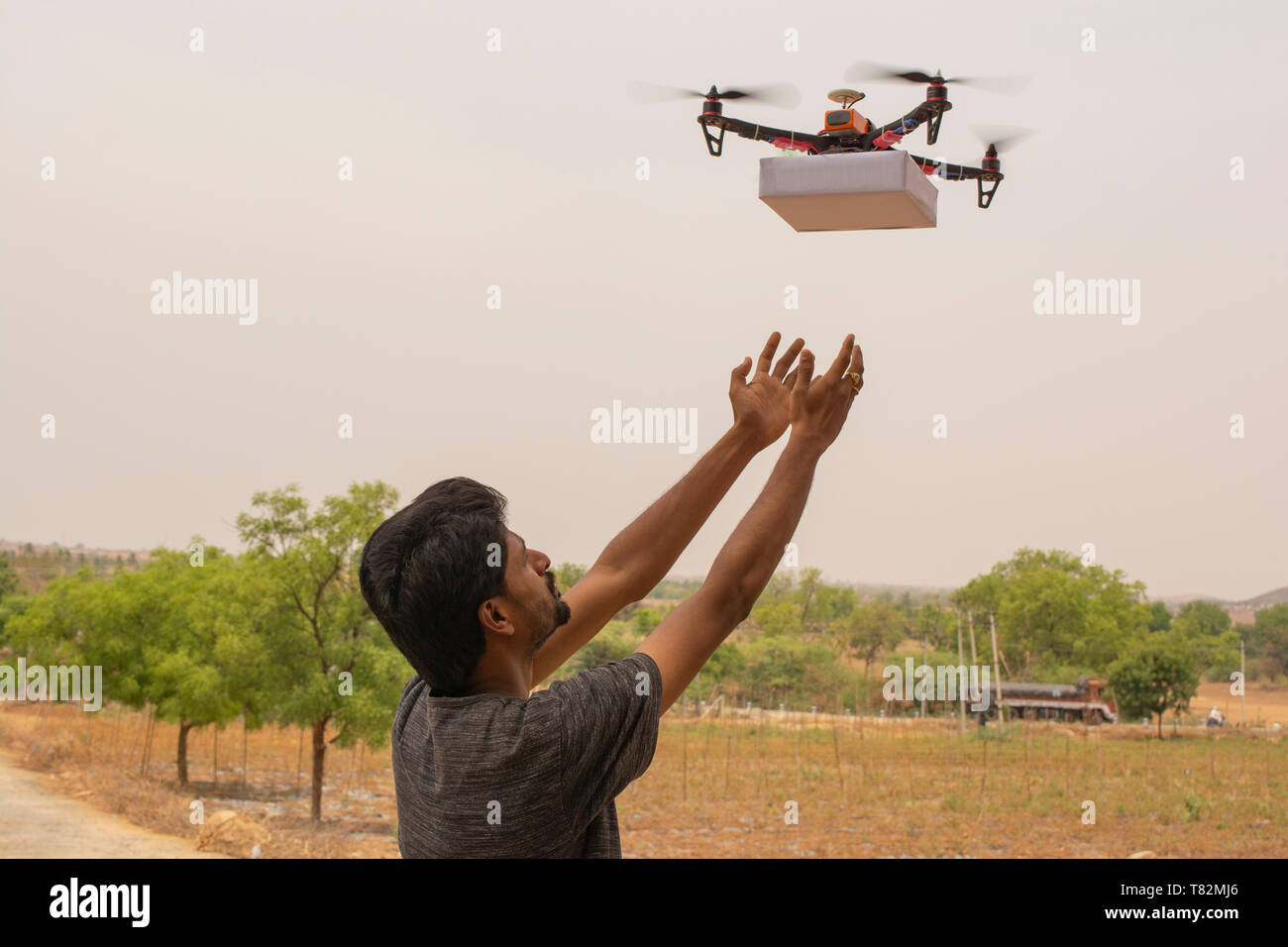Concetto di fuco consegna,giovane uomo che riceve il prodotto da flying drone. Foto Stock
