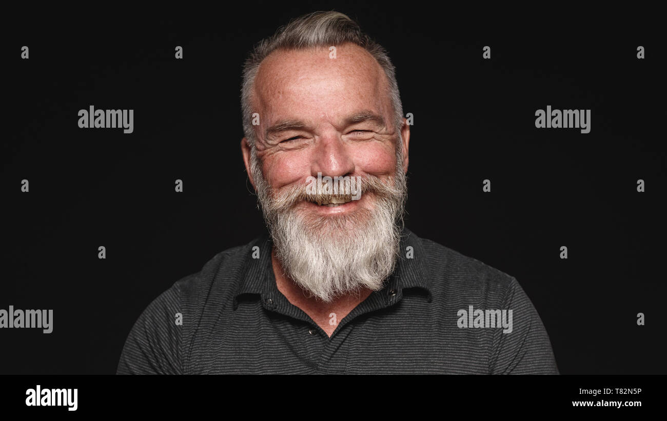 Close up di sorridere senior uomo con la barba bianca. Ritratto di un anziano uomo isolato su sfondo nero. Foto Stock