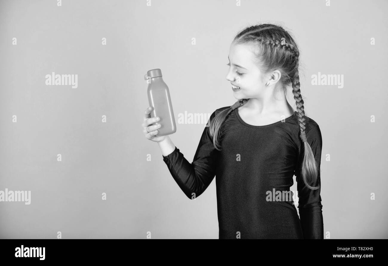 Kid carina ragazza sport ginnasta leotard tenere la bottiglia per bevande. Bilancio idrico e duro palestra di formazione. Bere più acqua. Conservare la bottiglia di acqua con voi. Di estinguere la sete. Bambino sente sete dopo sport training. Foto Stock