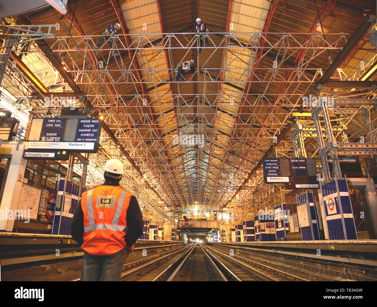 Stazione di Earls Court rinnovo, Londra, Regno Unito. Ponteggiatore orologi colleghi fasci di installazione sulle tracce durante una notte tempo di possesso. Foto Stock