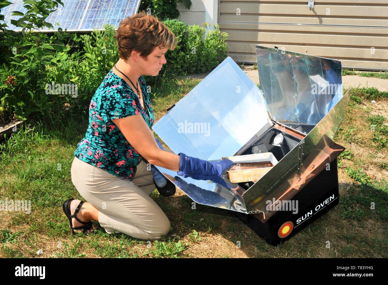 La donna il lievito da pane fresco con la fattoria-sollevati gli ingredienti in un forno di Sun, la cottura di alimenti con il calore del sole, nel Wisconsin, USA Foto Stock