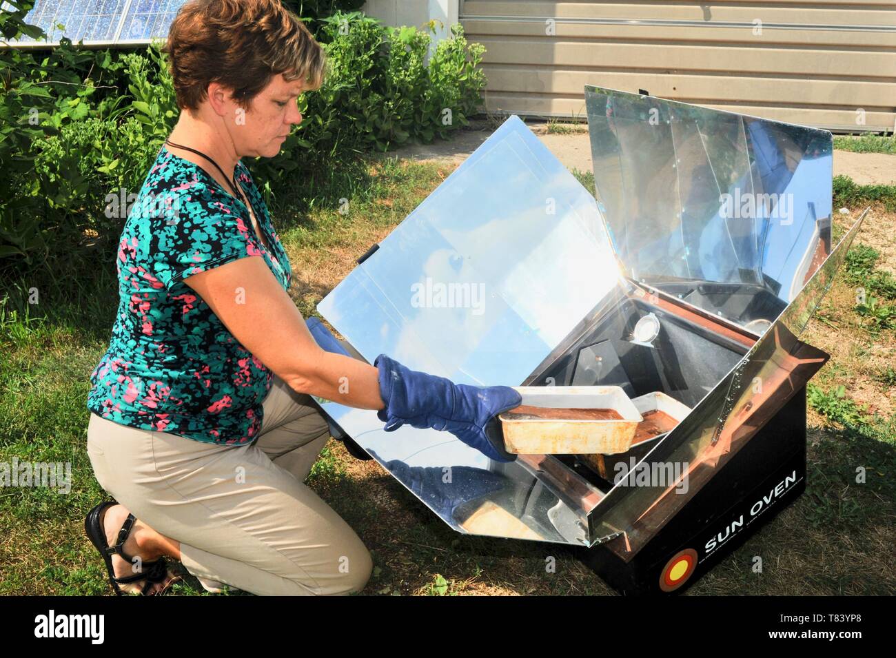 La donna il lievito da pane fresco con la fattoria-sollevati gli ingredienti in un forno di Sun, la cottura di alimenti con il calore del sole, nel Wisconsin, USA Foto Stock