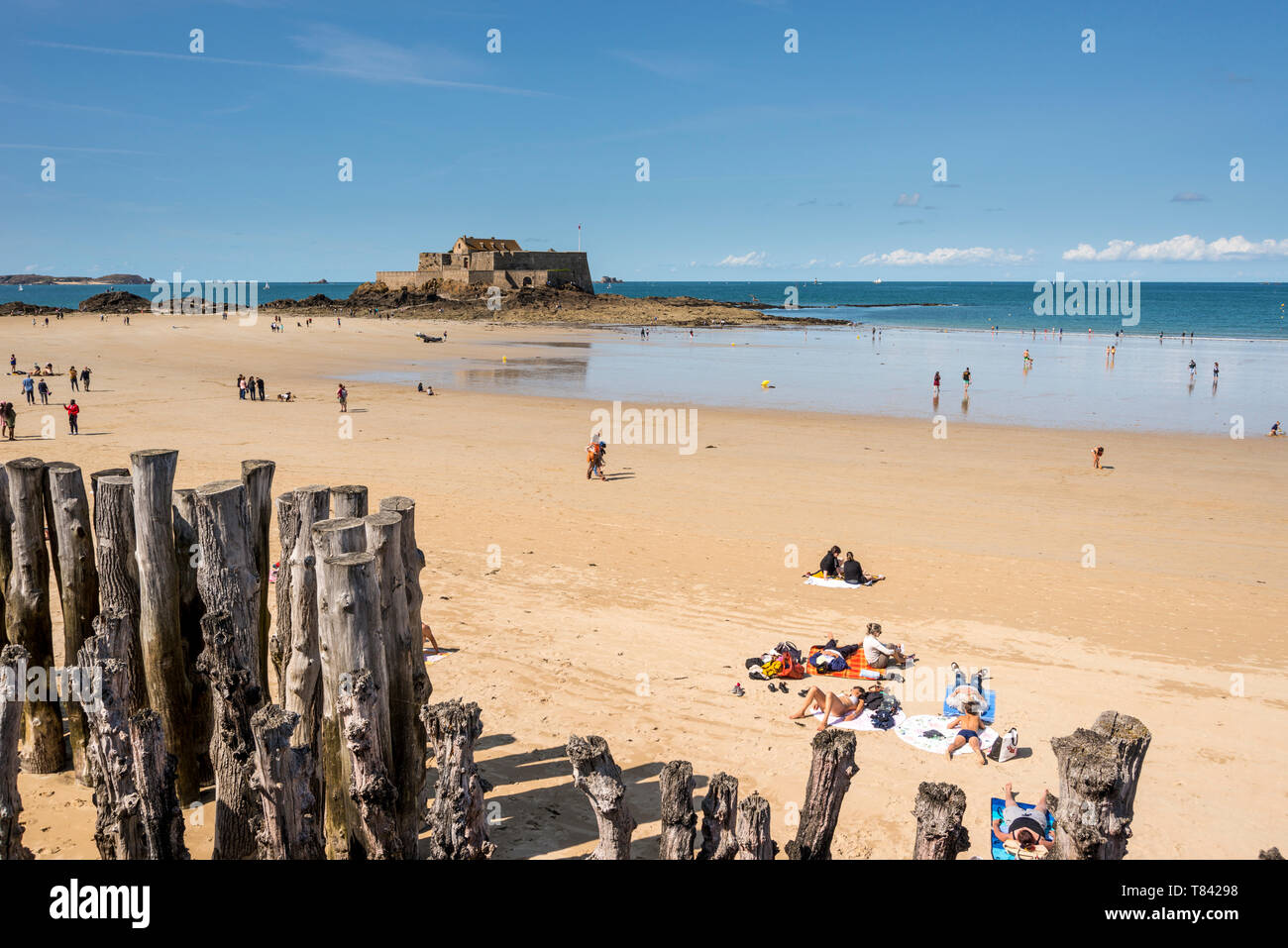 La gente sulla spiaggia sabbiosa e la vista del mare con il Fort National in background, Bretagna Francia Foto Stock