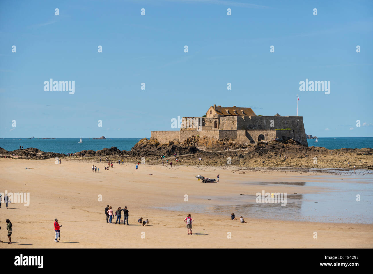 La gente sulla spiaggia sabbiosa e la vista del mare con il Fort National in background, Bretagna Francia Foto Stock