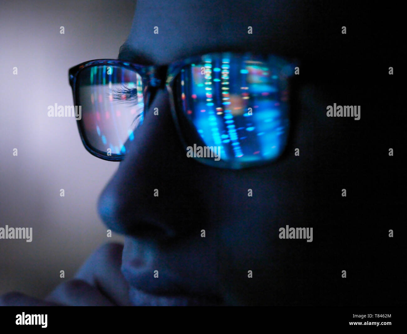 La ricerca genetica, sullo schermo del computer la riflessione negli occhiali di un profilo del DNA, close up di faccia Foto Stock