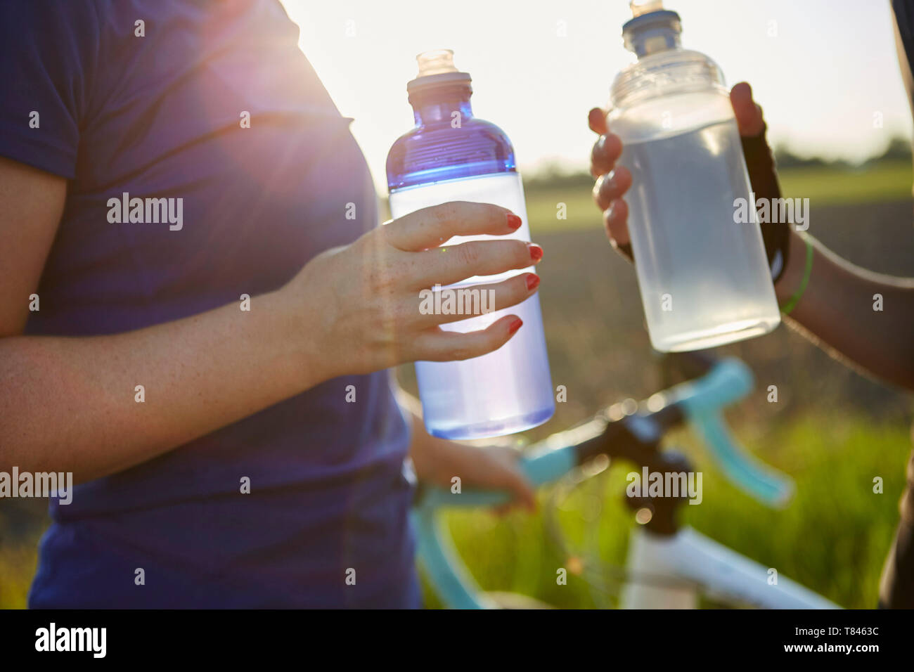 Due ciclisti femmina tenendo le bottiglie di acqua, metà sezione Foto Stock