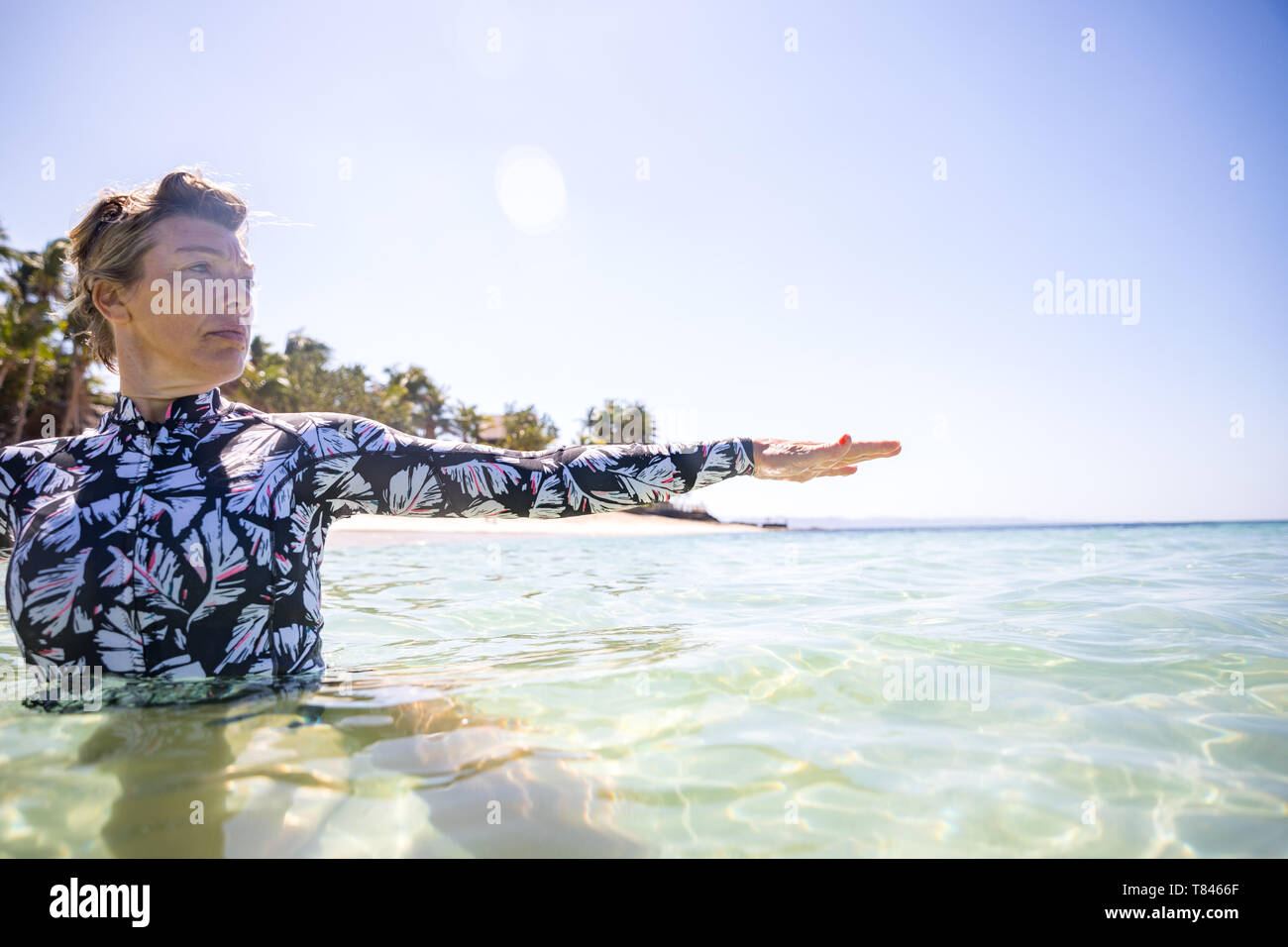 Donna stretching mano in mare, Pagudpud, Ilocos Norte, Filippine Foto Stock