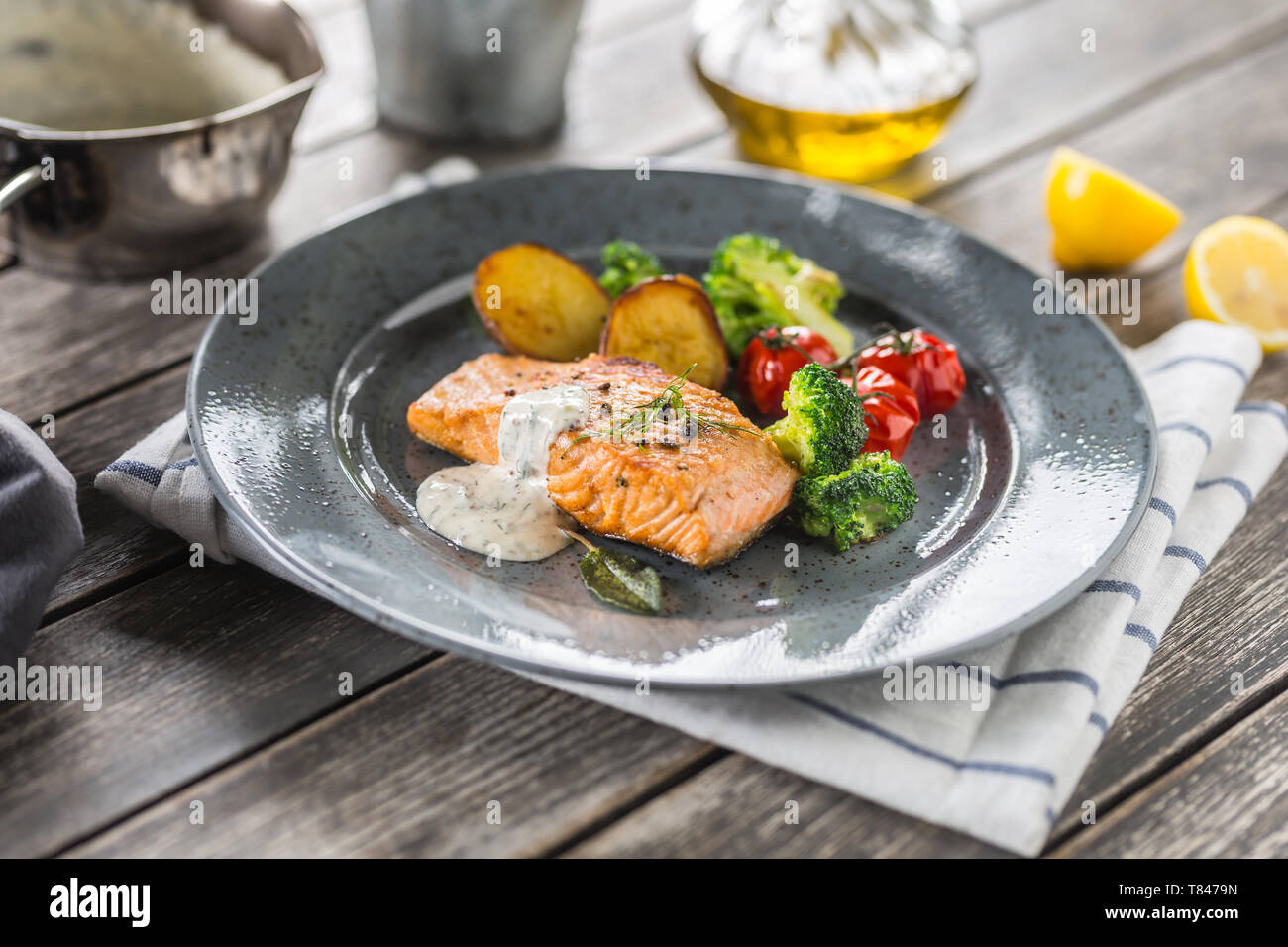 Arrosto di filetto di salmone broccoli pomodori e patate fritte con aneto salsa alla panna Foto Stock