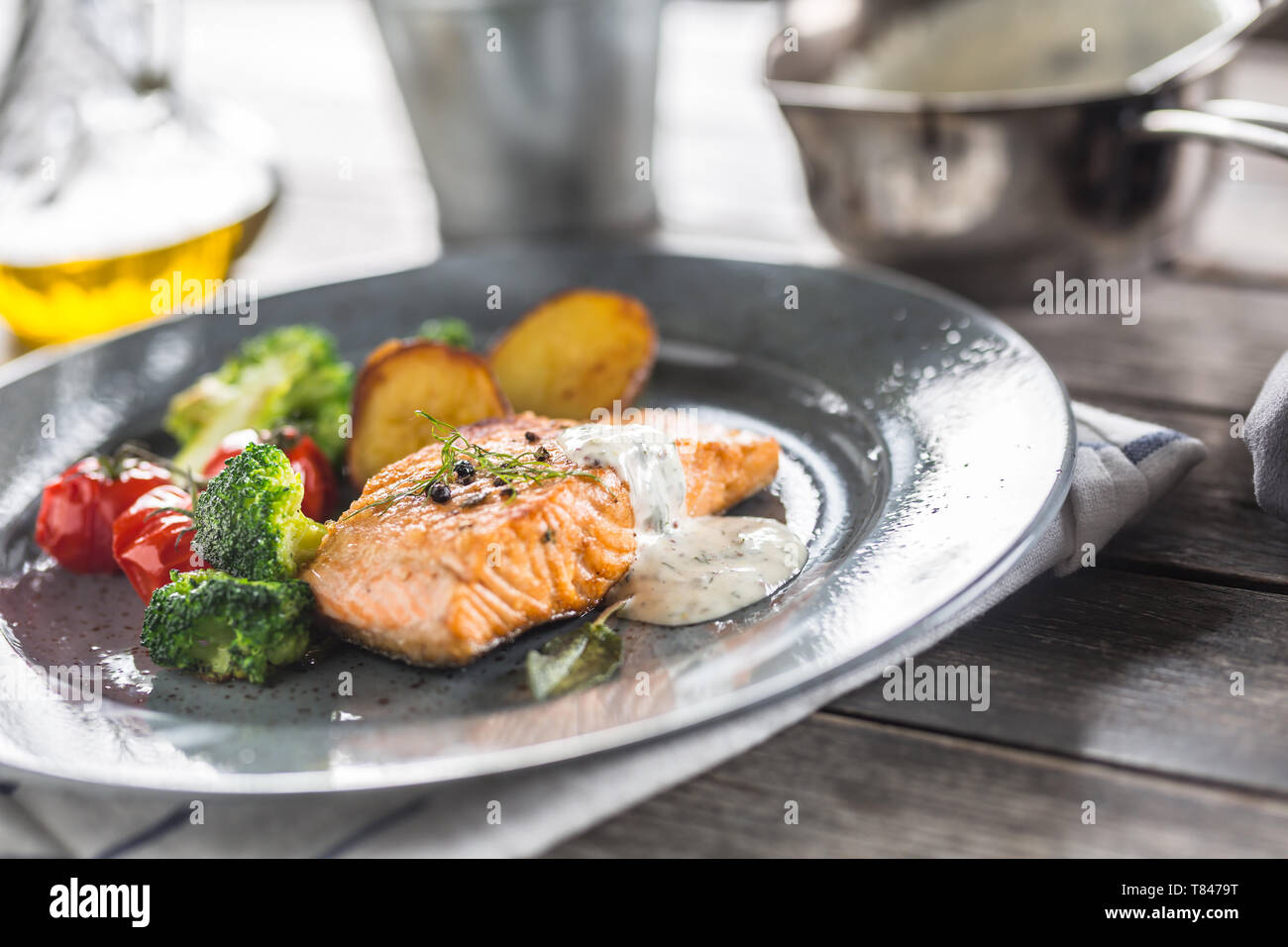 Arrosto di filetto di salmone broccoli pomodori e patate fritte con aneto salsa alla panna Foto Stock