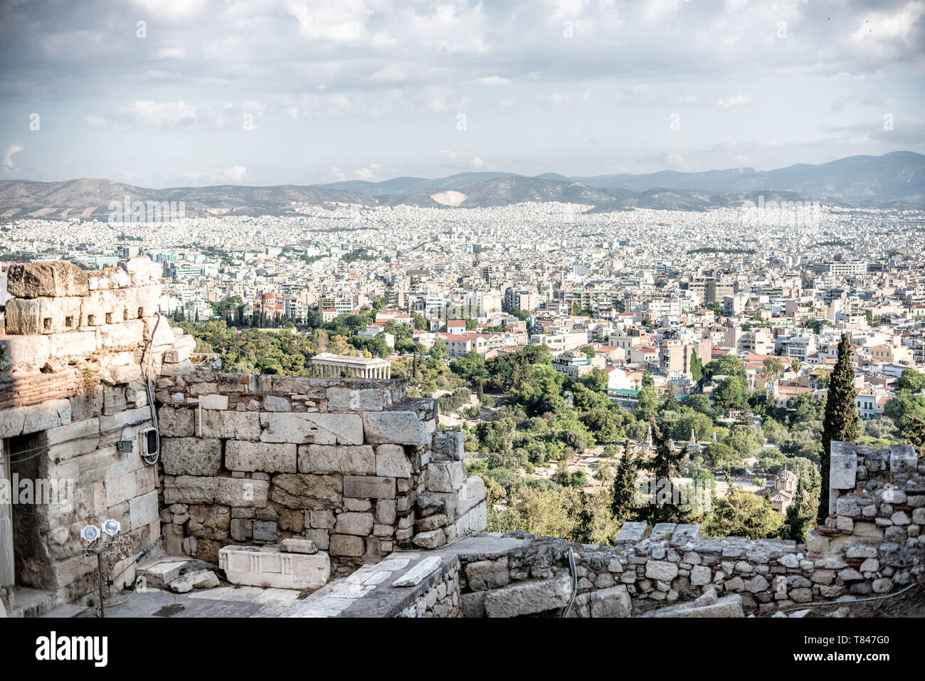 Paesaggio urbano di Atene Vista panoramica dall'Acropoli Patrimonio dell'UNESCO Grecia | ATENE — I tetti fitti del centro di Atene si estendono sotto le antiche mura fortificate dell'Acropoli, con la colonnata dorica del Tempio di Efesto visibile tra gli alberi dell'Antica Agorà sottostante. L'Acropoli domina la città da più di tre millenni da circa 512 piedi (156 m) sopra il bacino, le sue mura risalenti in parte a un circuito miceneo del XIII secolo a.C. Foto Stock