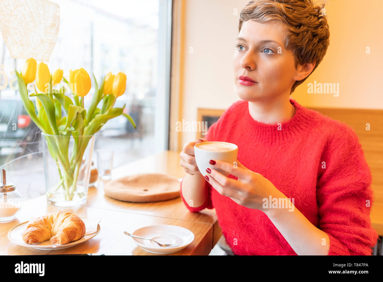 Metà donna adulta con corti capelli biondi guardando attraverso la finestra cafe Foto Stock