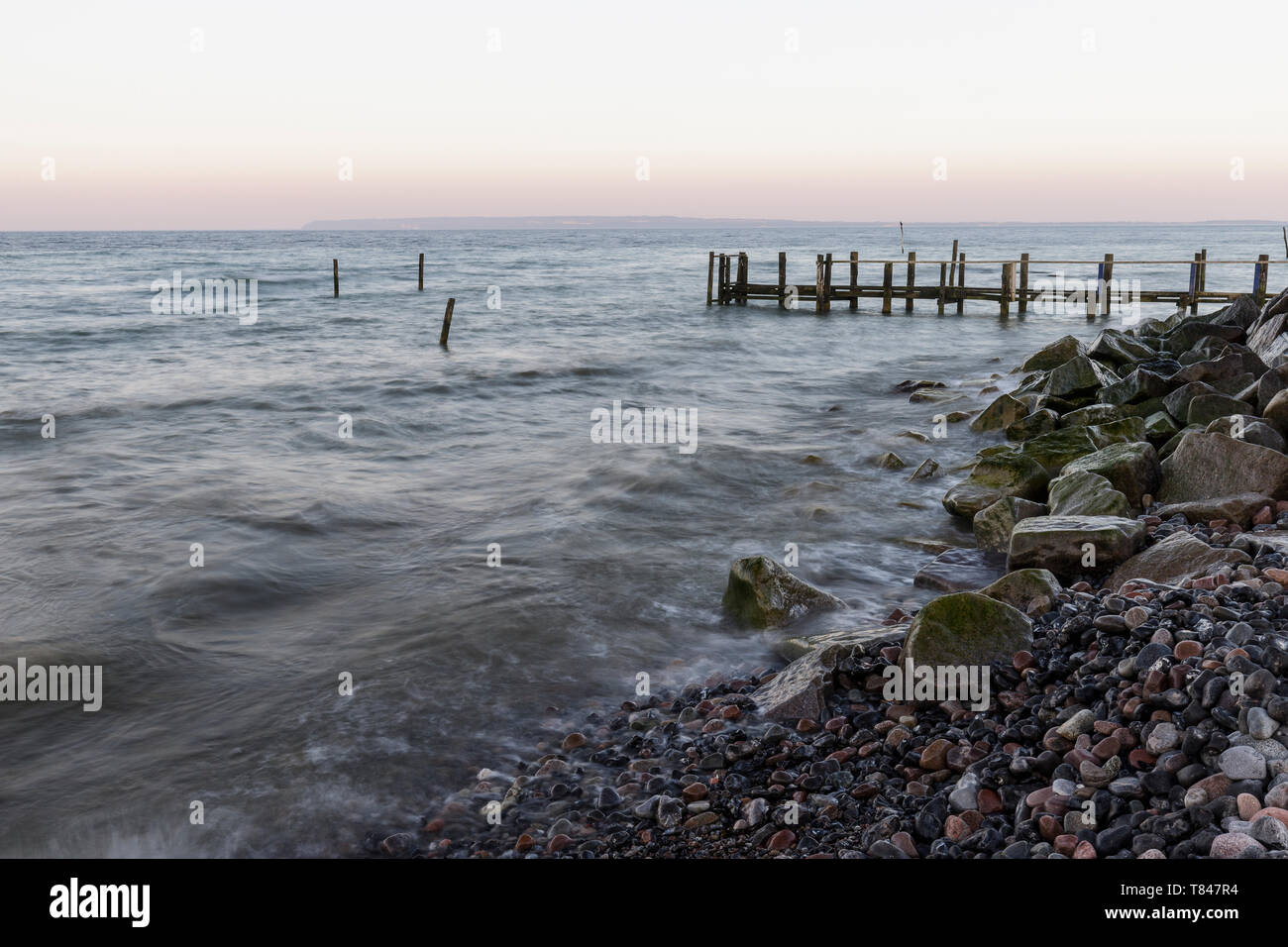 Il molo di legno e la spiaggia rocciosa al crepuscolo, Putgarten, Rügen, Meclenburgo-Pomerania Occidentale, Germania Foto Stock