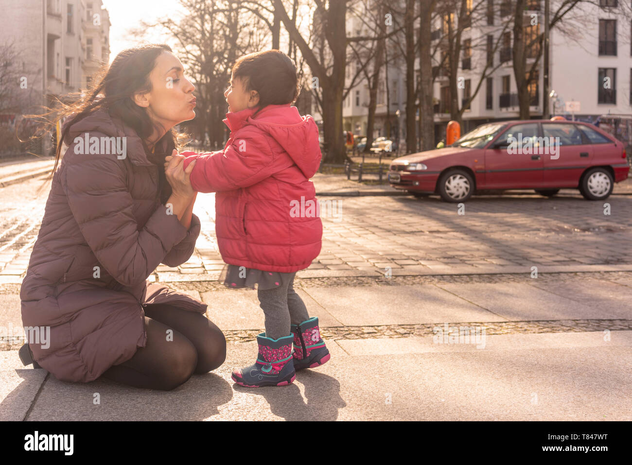 Madre baciare figlia sul marciapiede Foto Stock