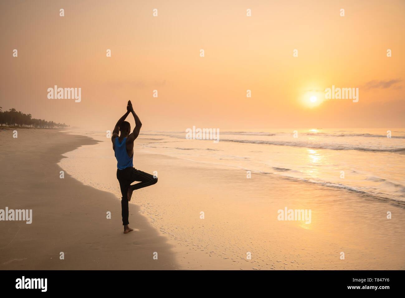 Uomo a praticare yoga sulla spiaggia Foto Stock