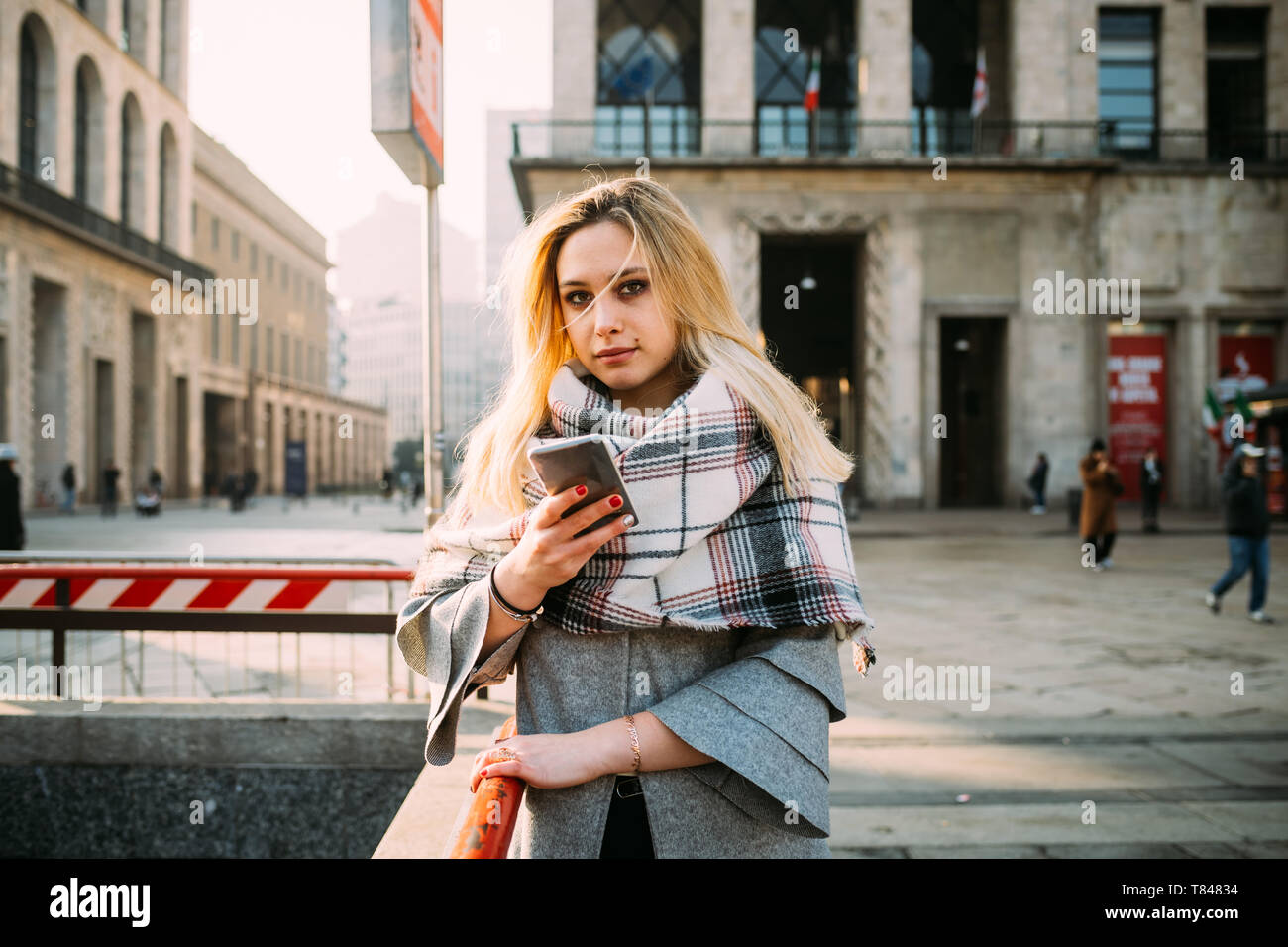 Giovane donna con lo smartphone dalla stazione della metropolitana, ritratto, Milano, Italia Foto Stock