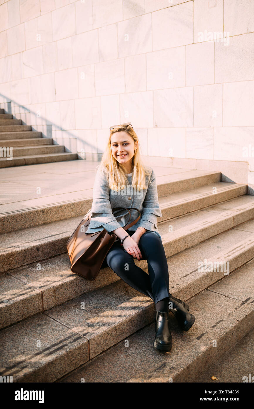 Giovane donna seduta sulla scalinata della città, ritratto Foto Stock