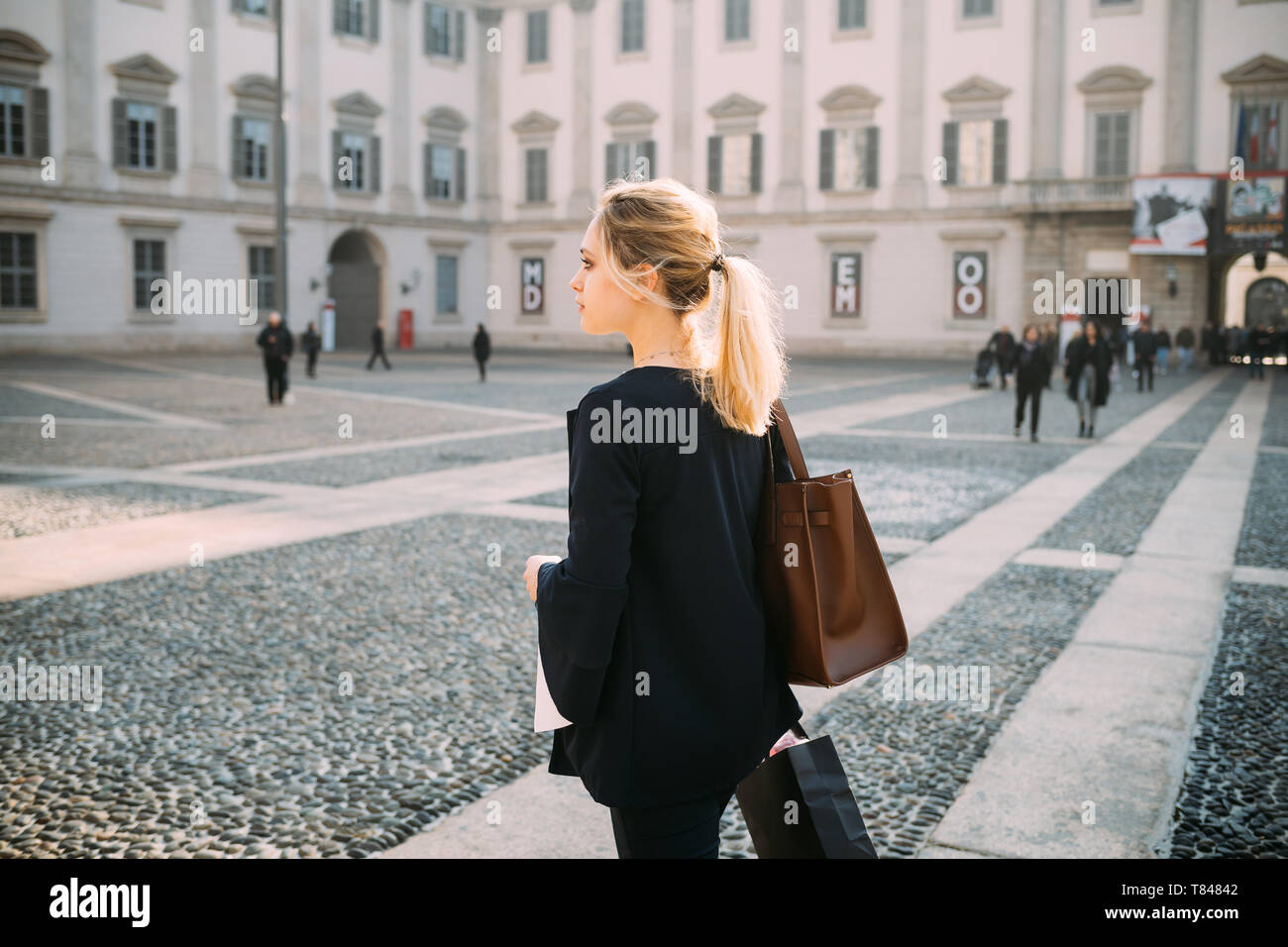 Giovane turista femminile con le borse della spesa in city square, Milano, Italia Foto Stock