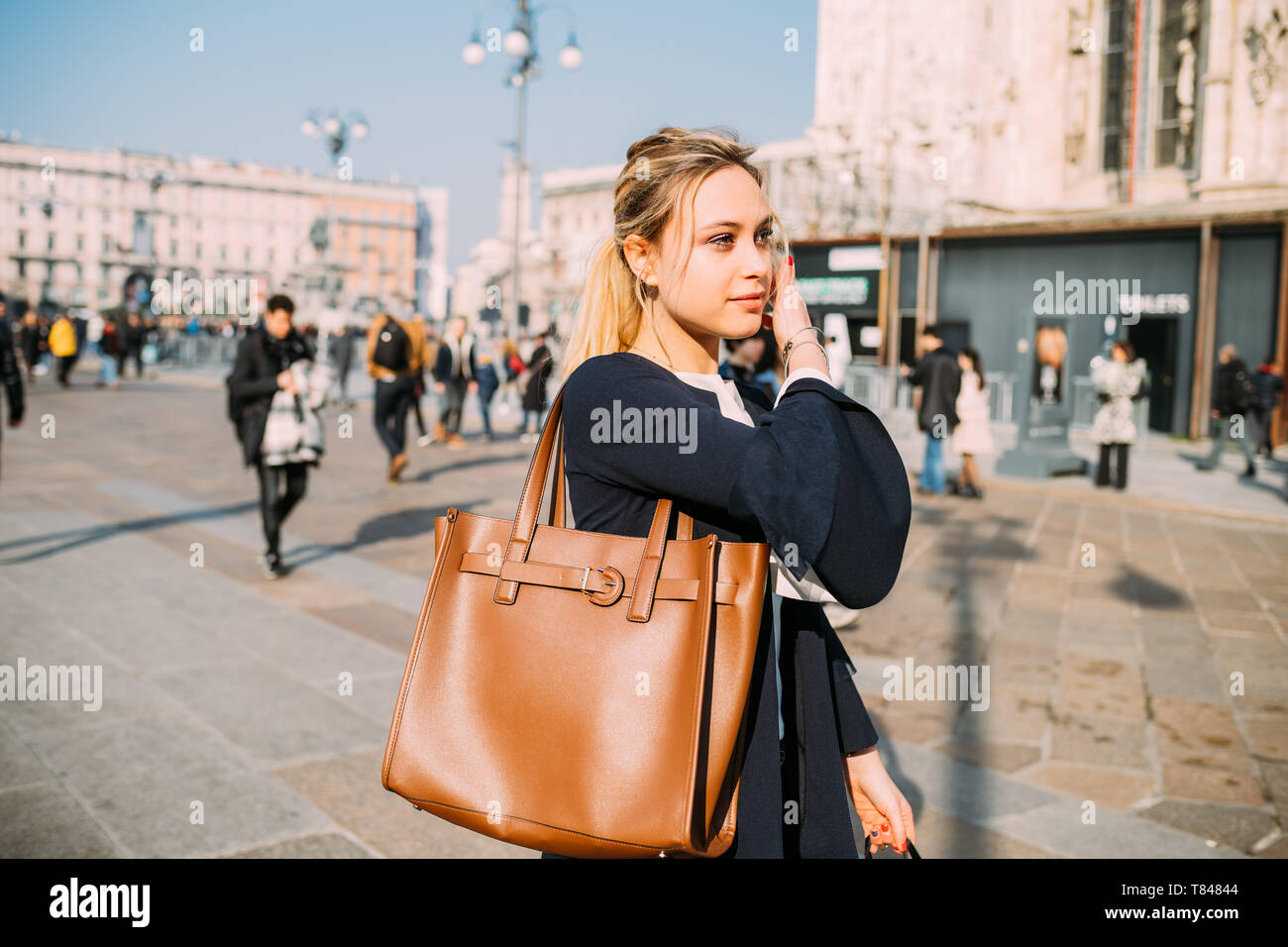 Giovane turista femminile passeggiando e ascolto di cuffie in city square, Milano, Italia Foto Stock