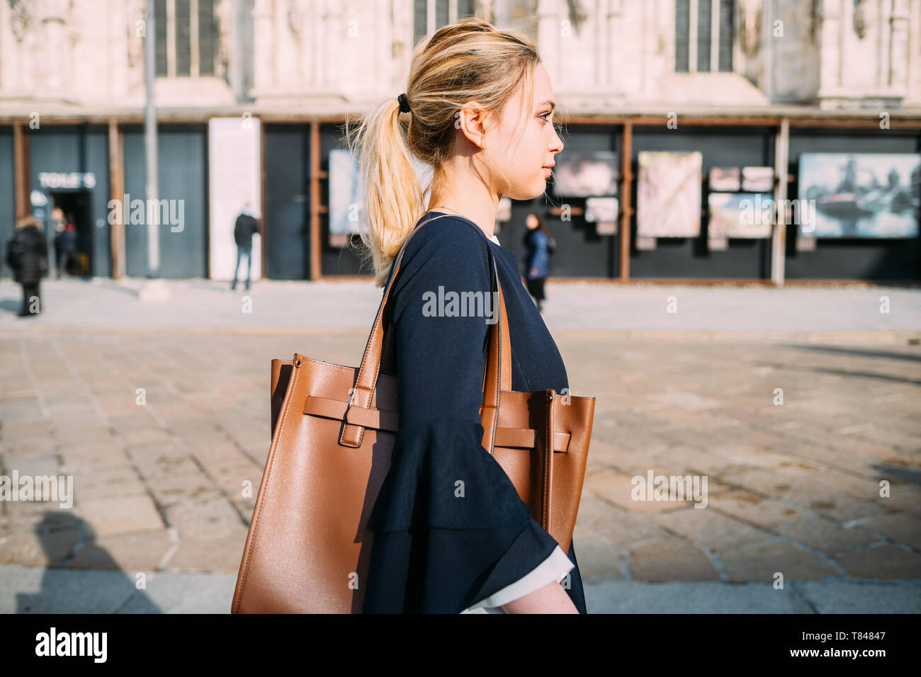 Giovane turista femminile passeggiando e ascoltando le cuffie in una strada di città Foto Stock