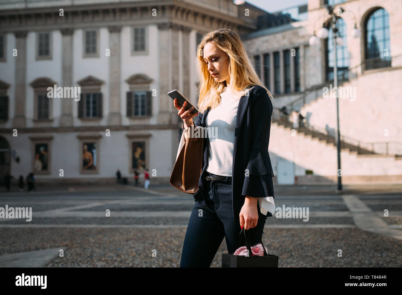 Giovane turista femminile guardando lo smartphone nel city square, Milano, Italia Foto Stock