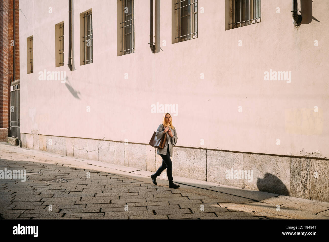 Giovane donna passeggiando lungo una strada di città Foto Stock