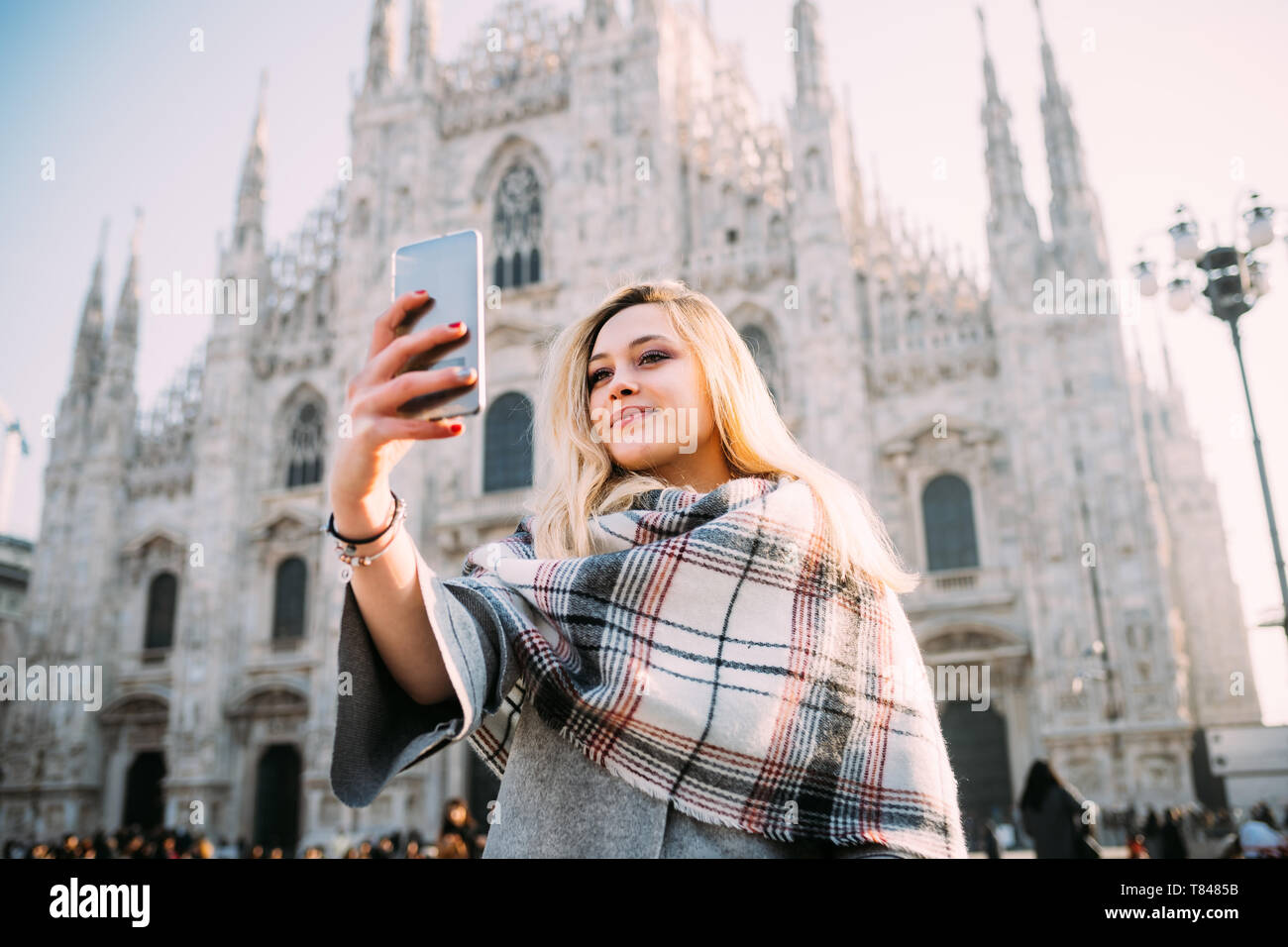 Giovani femmine turistica prendendo selfie smartphone davanti al duomo di Milano, Milano, Italia Foto Stock