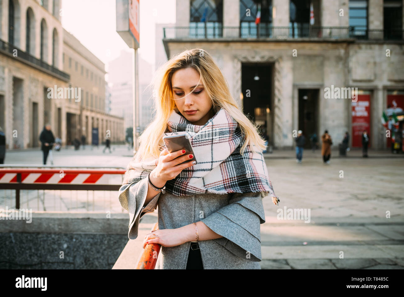 Giovane donna guardando smartphone su una strada di città Foto Stock