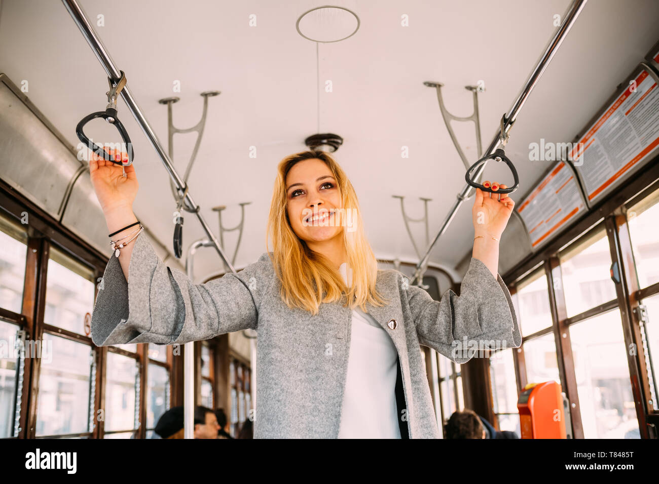 Giovane donna con capelli lunghi biondi sul tram della città Foto Stock