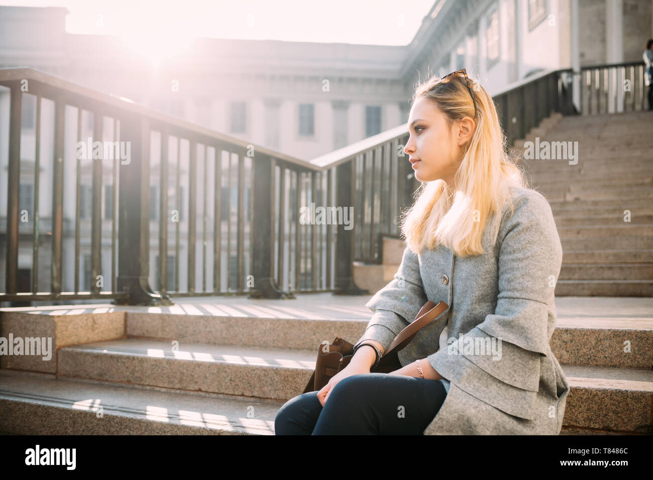 Giovane donna seduta sulla scalinata della città alla ricerca di distanza, Milano, Italia Foto Stock