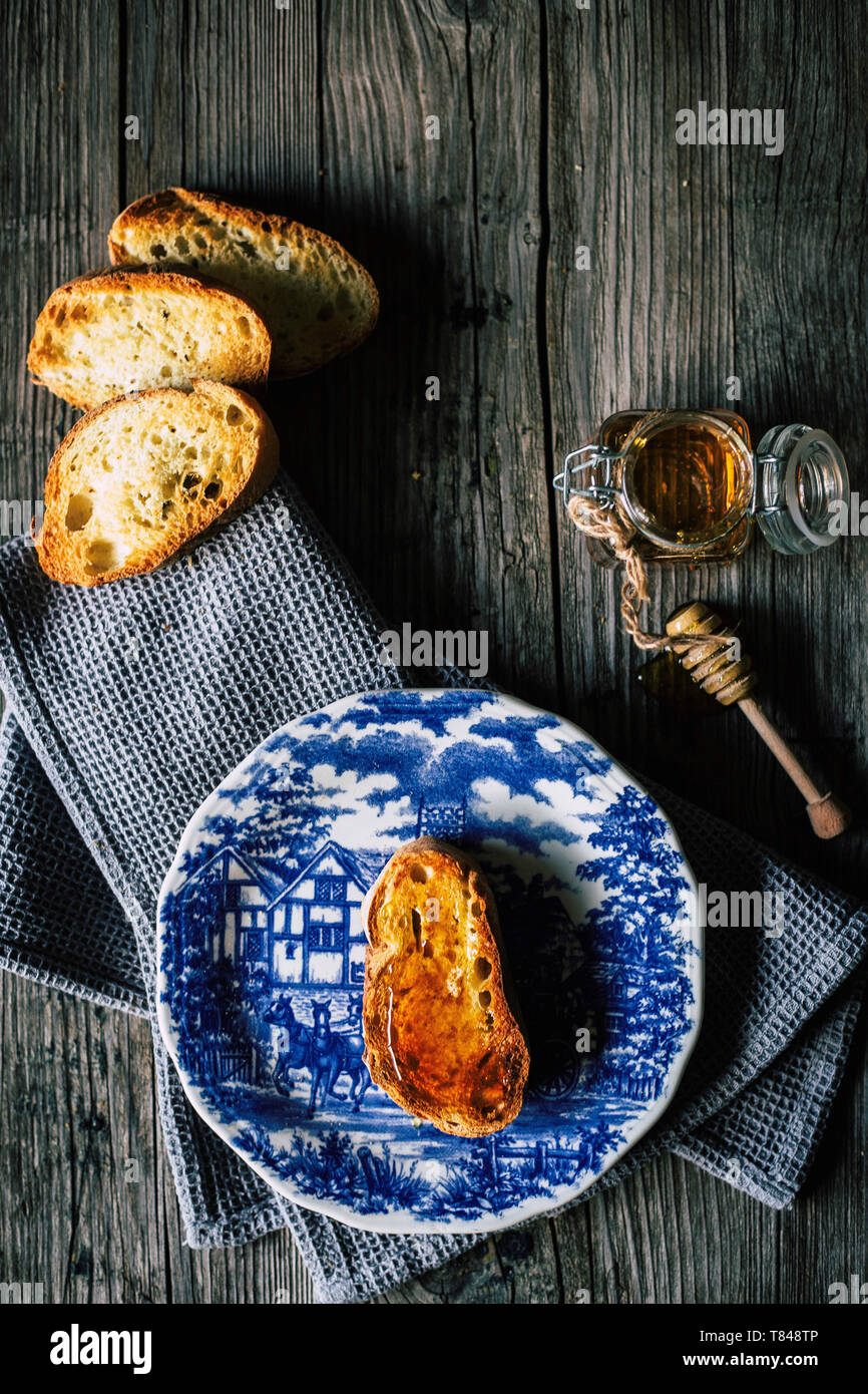 Fetta di baguette con miele sulla piastra Foto Stock