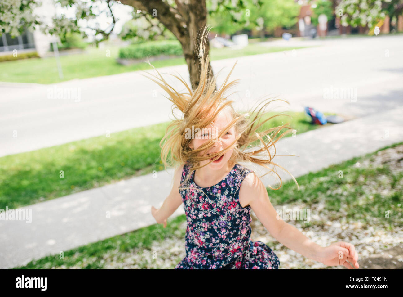 Ragazza con lunghi capelli biondi ballare sulla strada suburbana Foto Stock