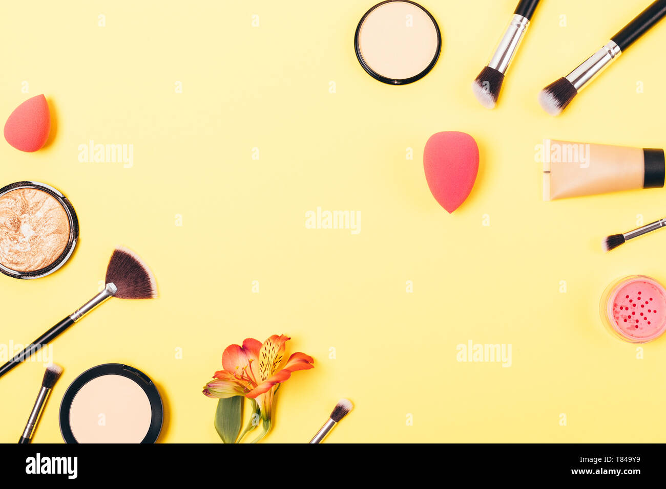 Di colore giallo brillante trucco sullo sfondo di prodotti cosmetici e accessori per anche carnagione, laici piana. Foto Stock