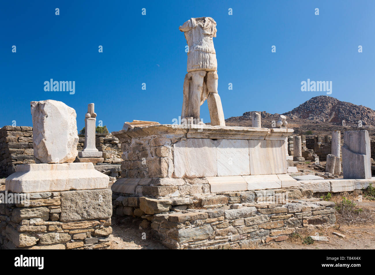 Delos, Mykonos, Egeo Meridionale, Grecia. Decapitati statua in piedi in mezzo a resti archeologici, Monte Kynthos in background. Foto Stock