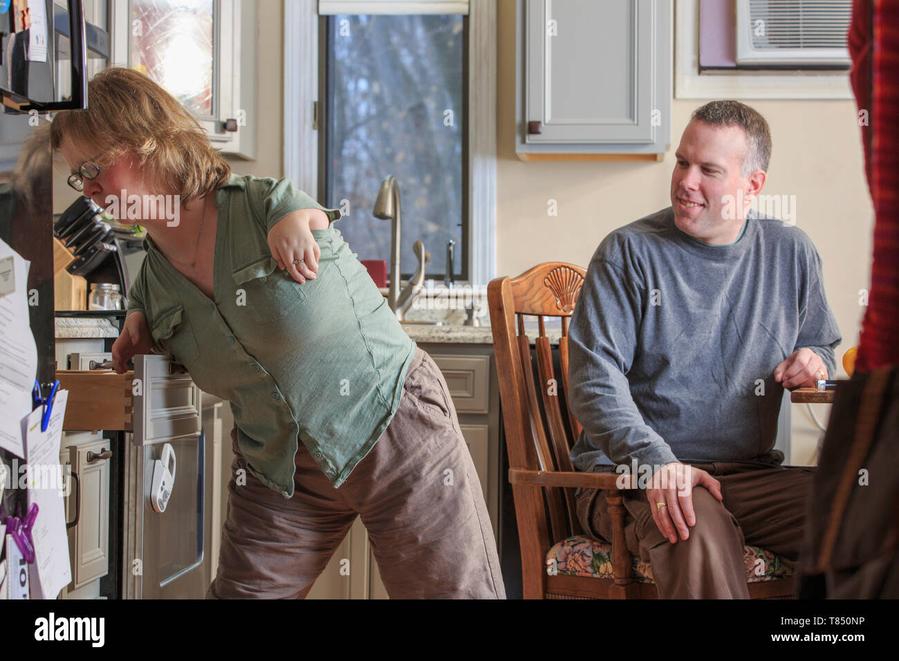 Donna con sindrome tar usando un cassetto da cucina con suo marito Foto Stock