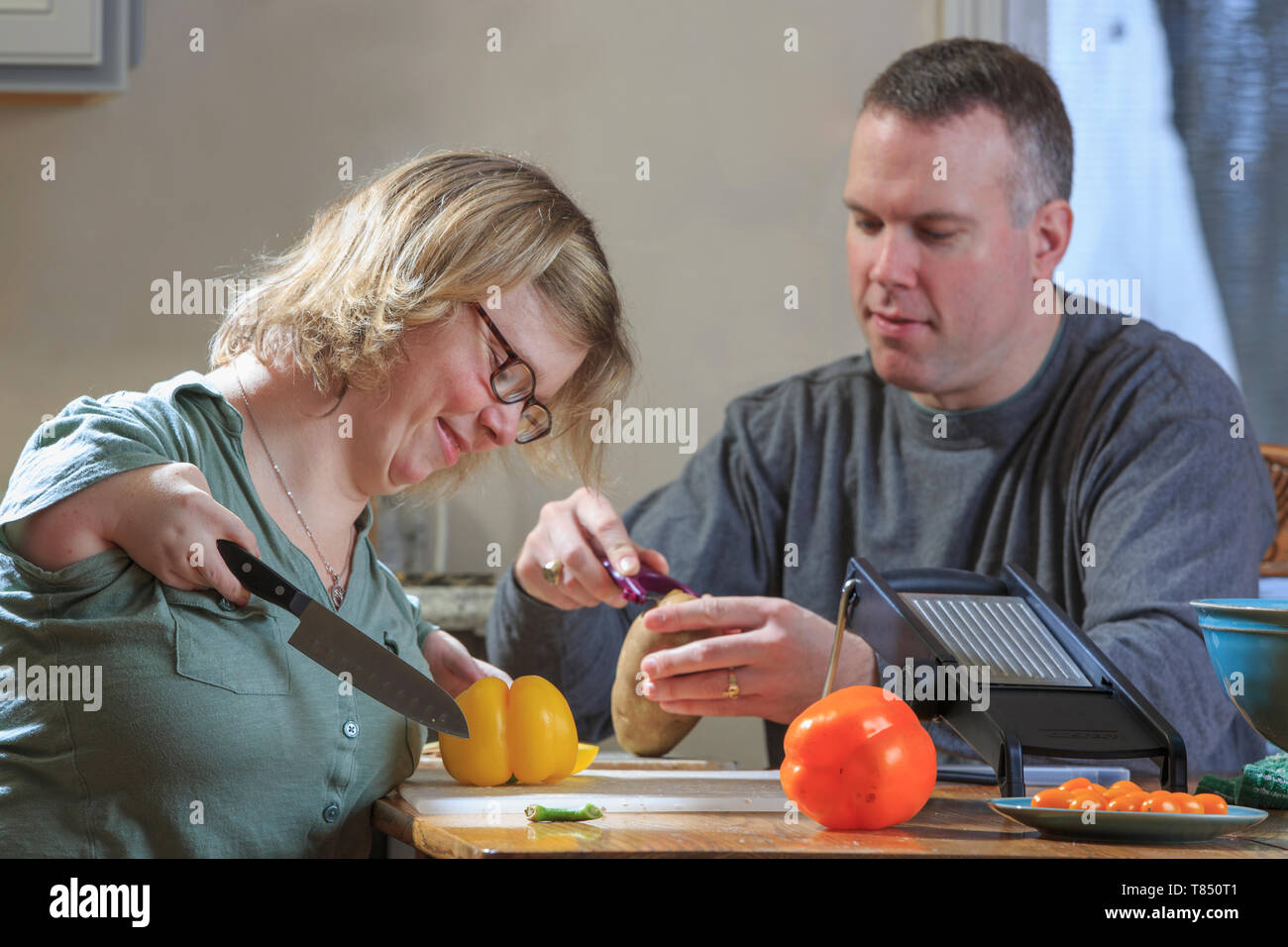 Donna con sindrome di catrame come tagliare le verdure con il marito in cucina Foto Stock