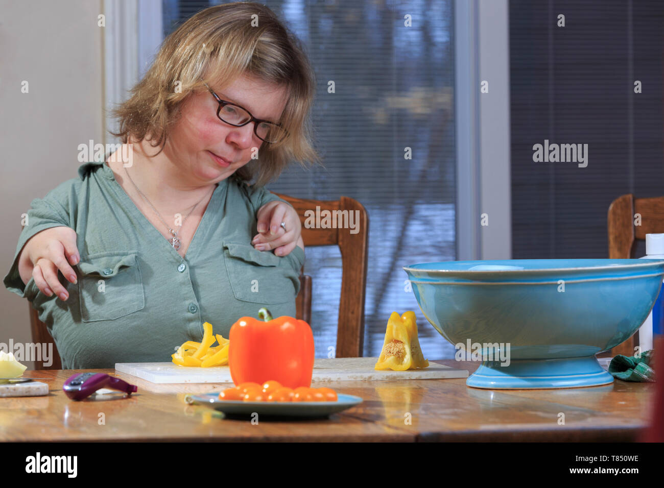 Donna con sindrome di catrame di preparare le verdure per la cena in cucina Foto Stock