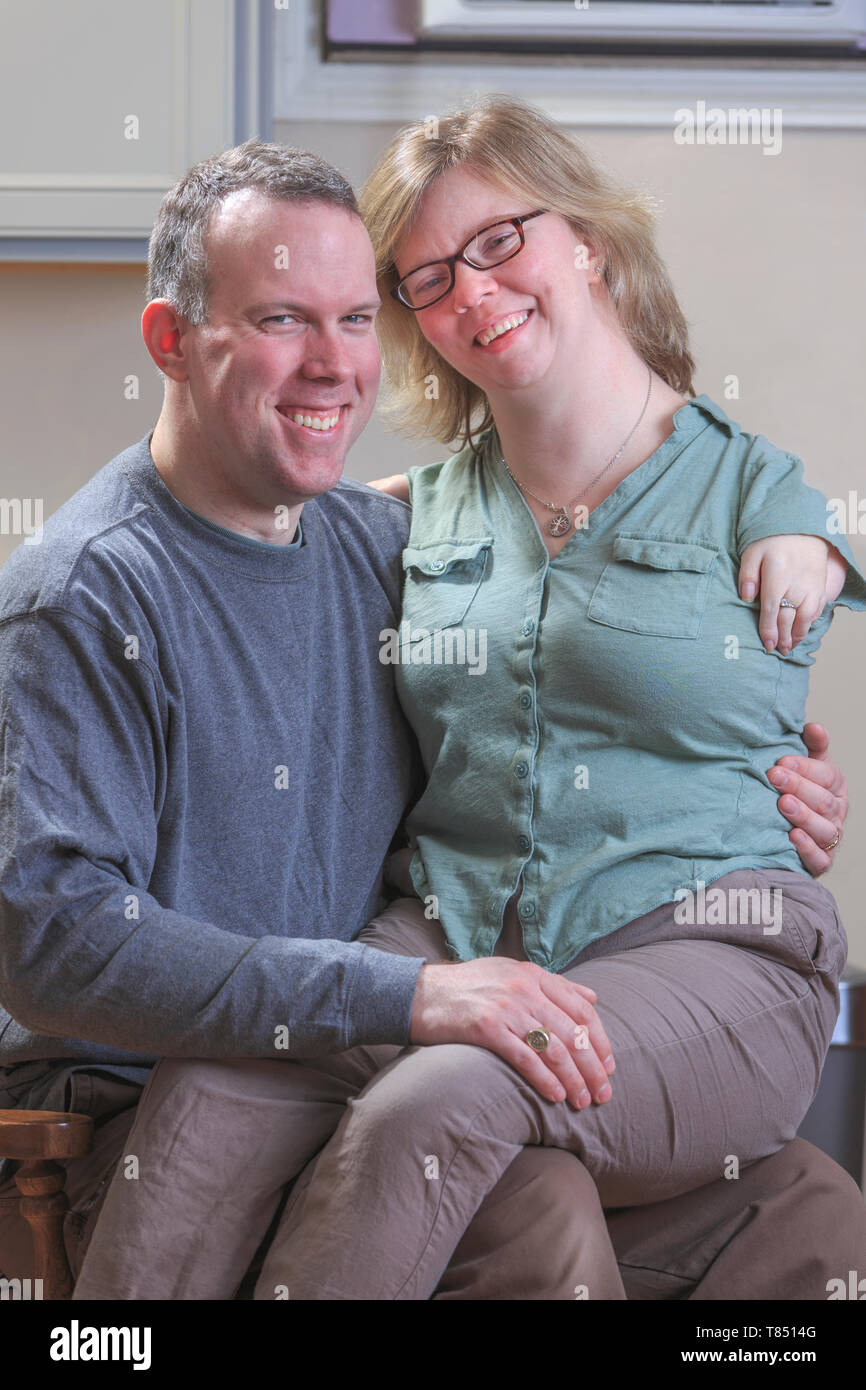 Donna con sindrome di catrame seduto sul suo marito lap Foto Stock