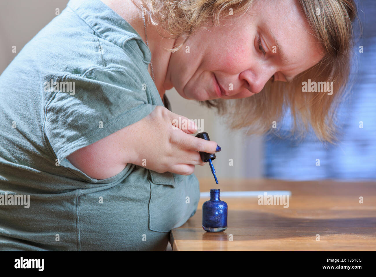 Donna con sindrome di catrame dipinto i suoi chiodi a casa Foto Stock